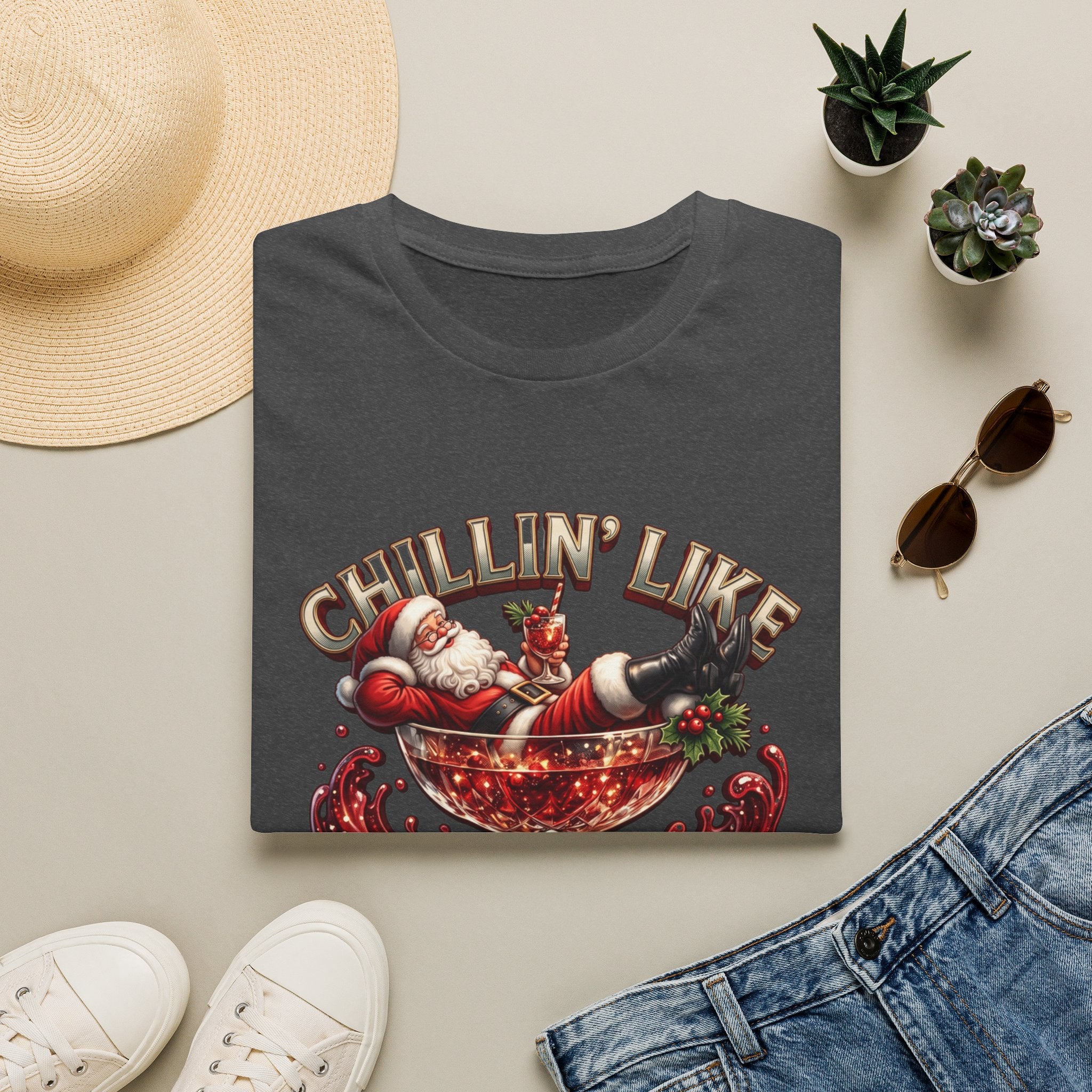 Chillin' Like a Kringle Santa print on a Dark Heather t-shirt, folded beside a straw hat and jeans