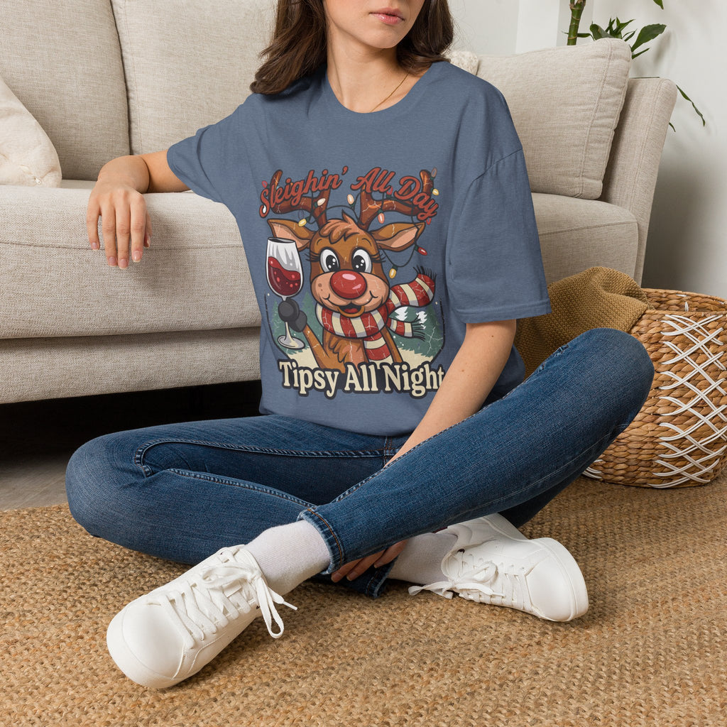 Reindeer Sleighin' All Day Tipsy All Night t-shirt in Heather Indigo, worn by a woman seated on a rug