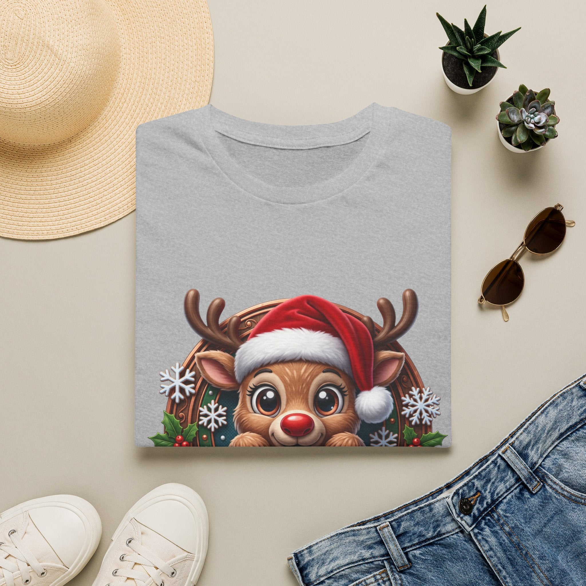 Cute Red-Nosed Reindeer print on a Sport Grey t-shirt, folded beside a straw hat and jeans