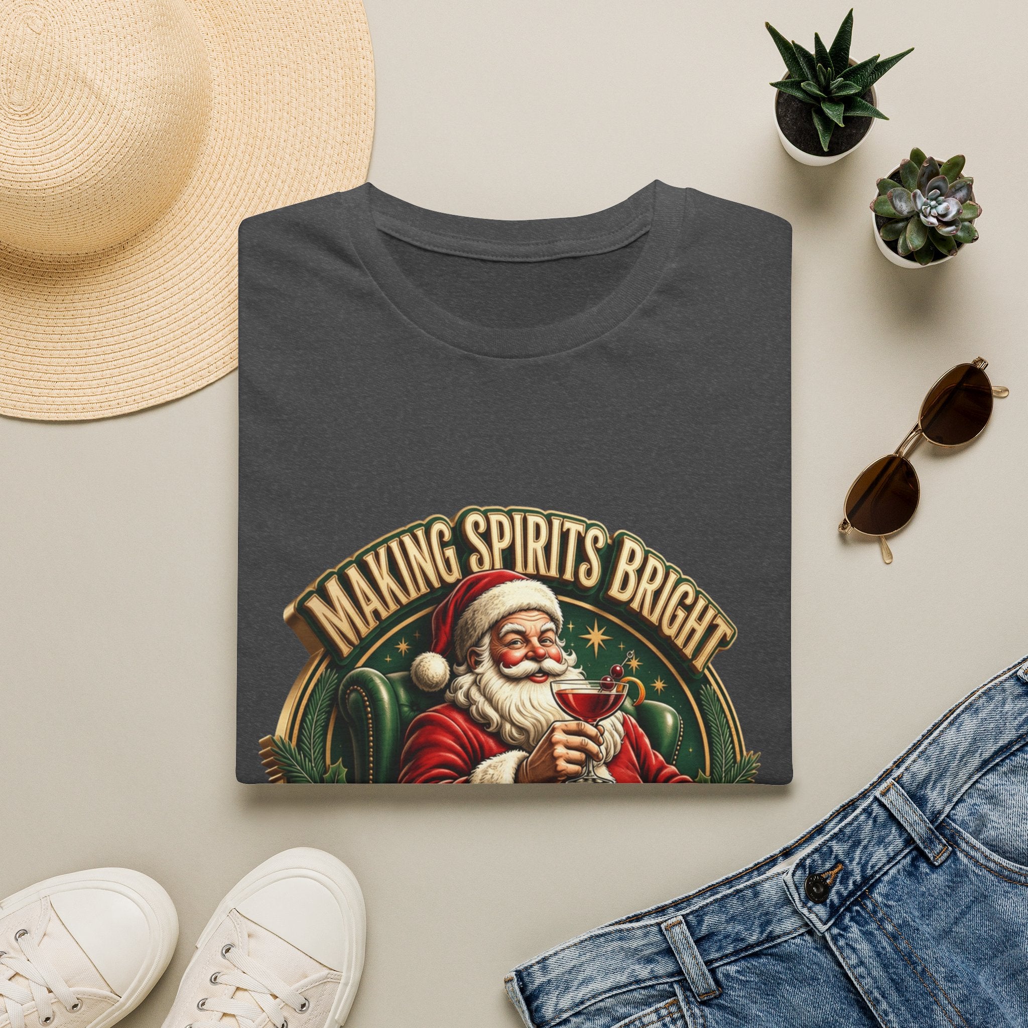 Making Spirits Bright and Stronger Santa print on a Dark Heather t-shirt, folded beside a straw hat and jeans