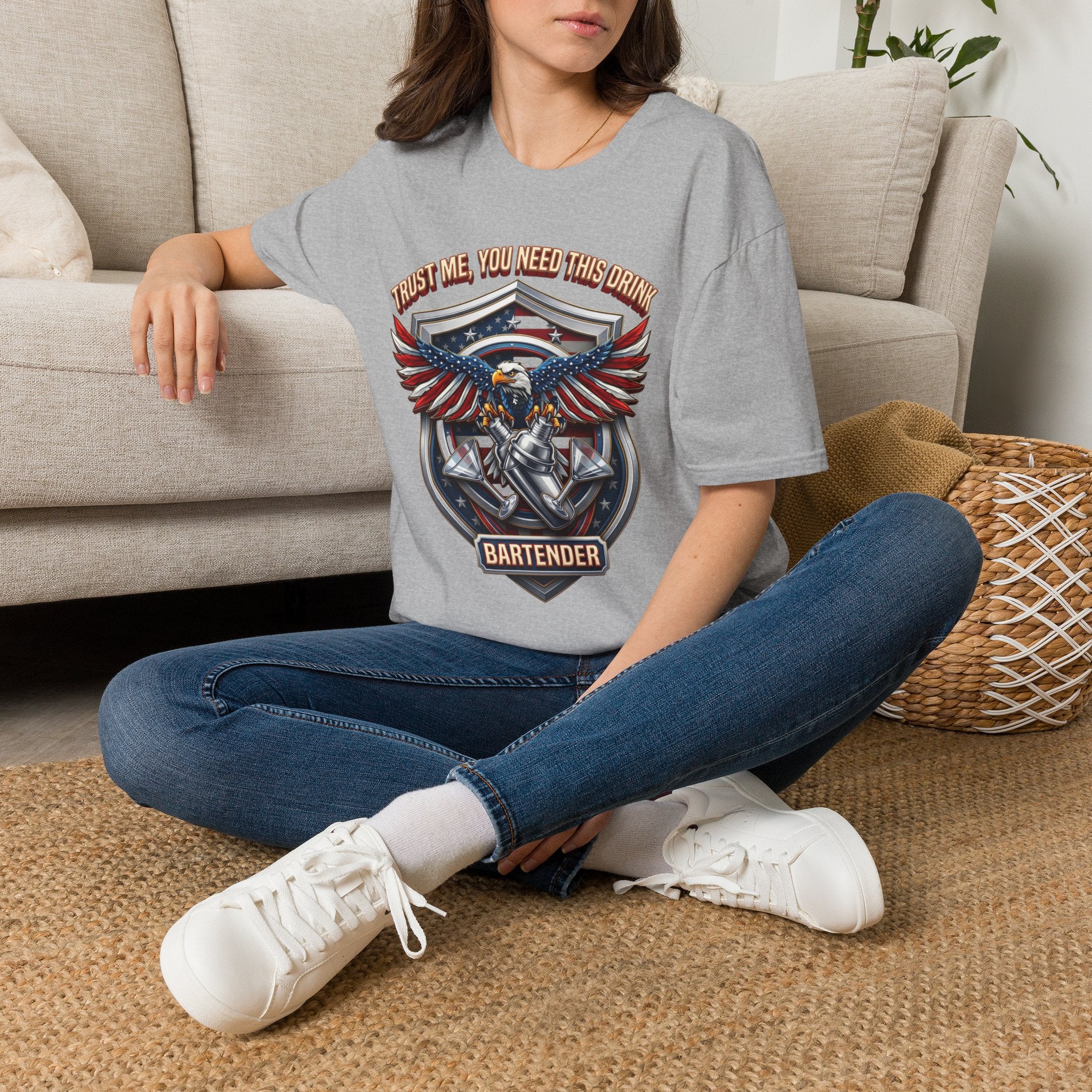 Bartender Eagle Trust Me You Need This Drink t-shirt in Sport Grey, worn by a woman seated on a rug