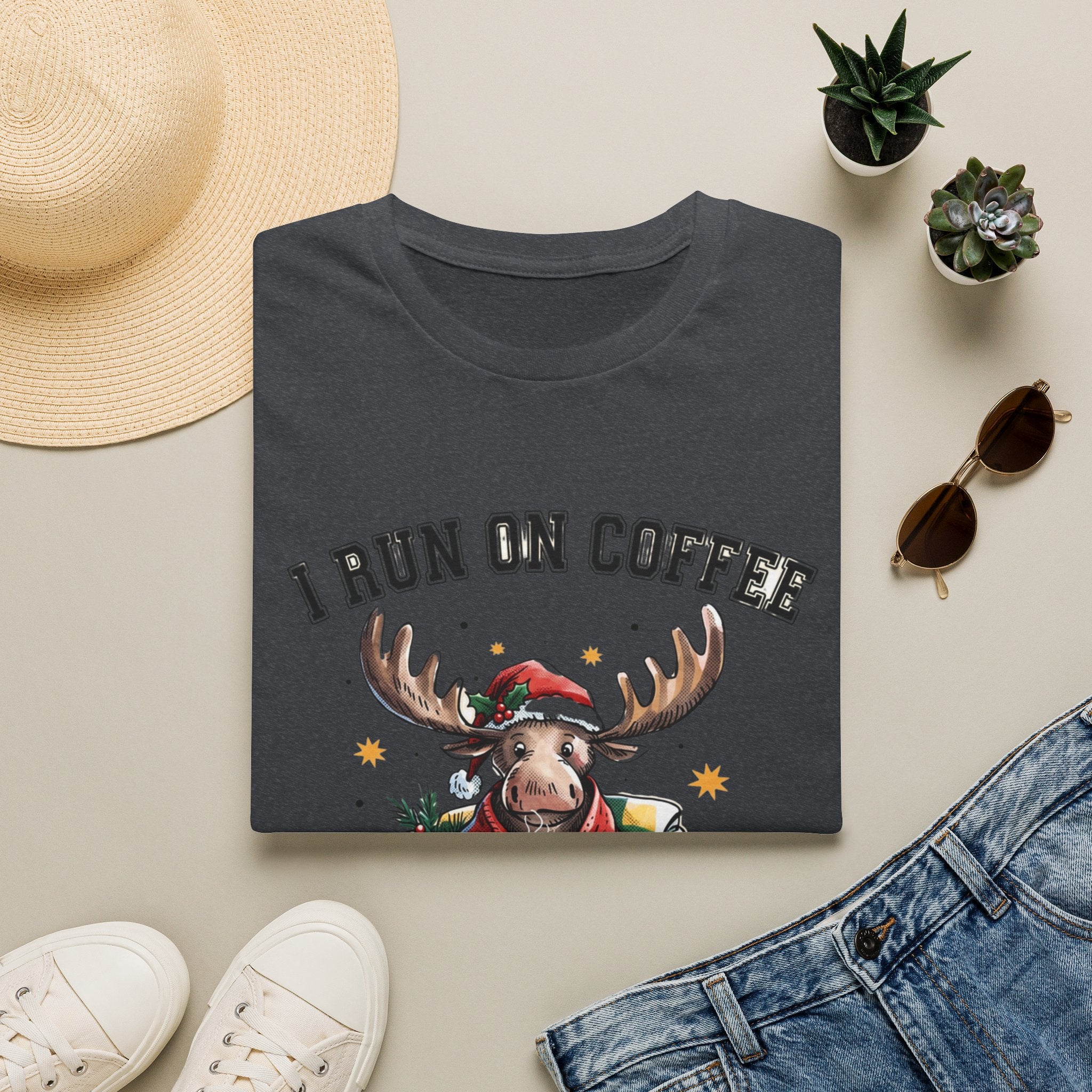 Moose I Run On Coffee and Sleighin' It print on a Dark Heather Grey t-shirt, folded beside a straw hat and jeans