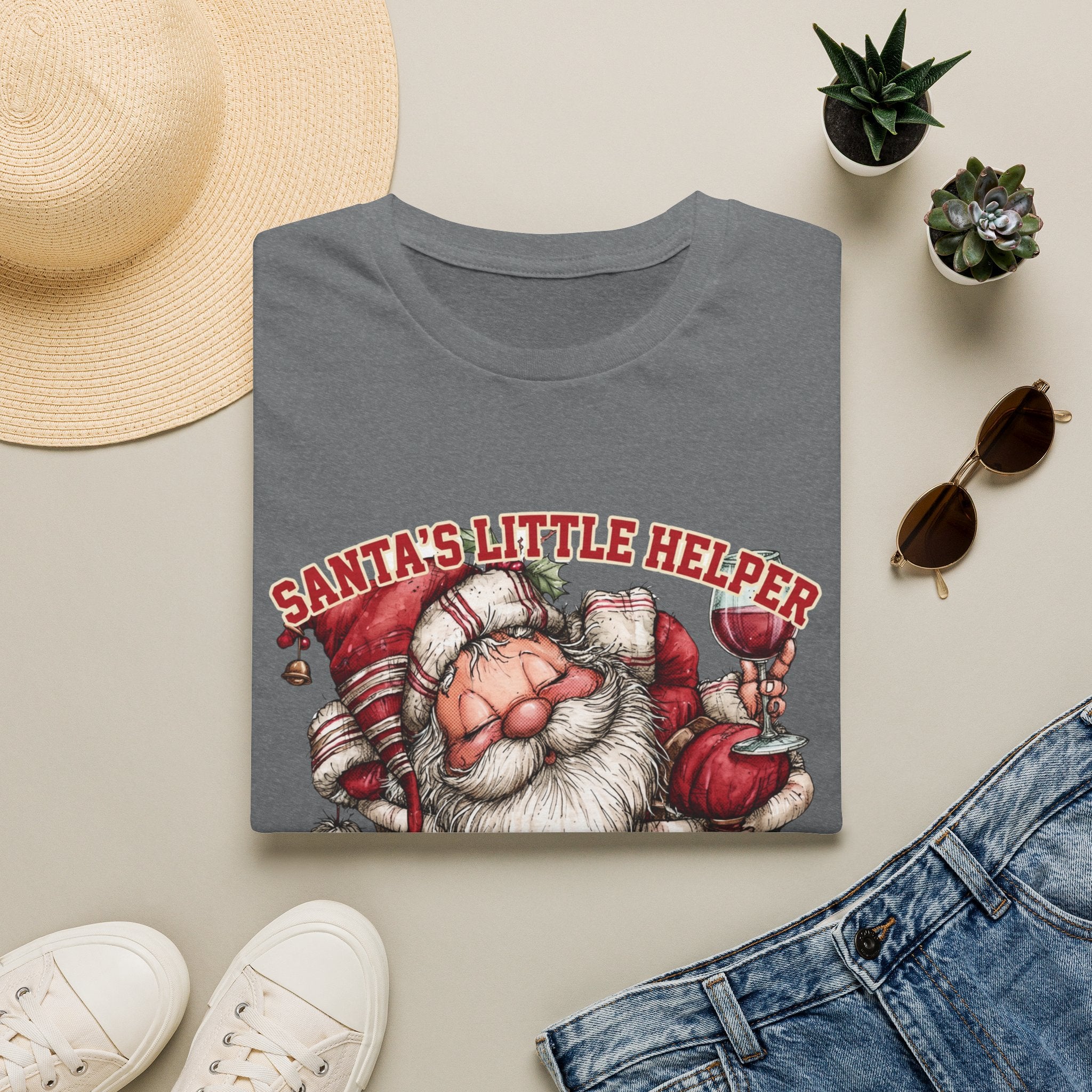 Santa's Little Helper Is Lit Christmas Wine print on a Graphite Heather t-shirt, folded beside a straw hat and jeans