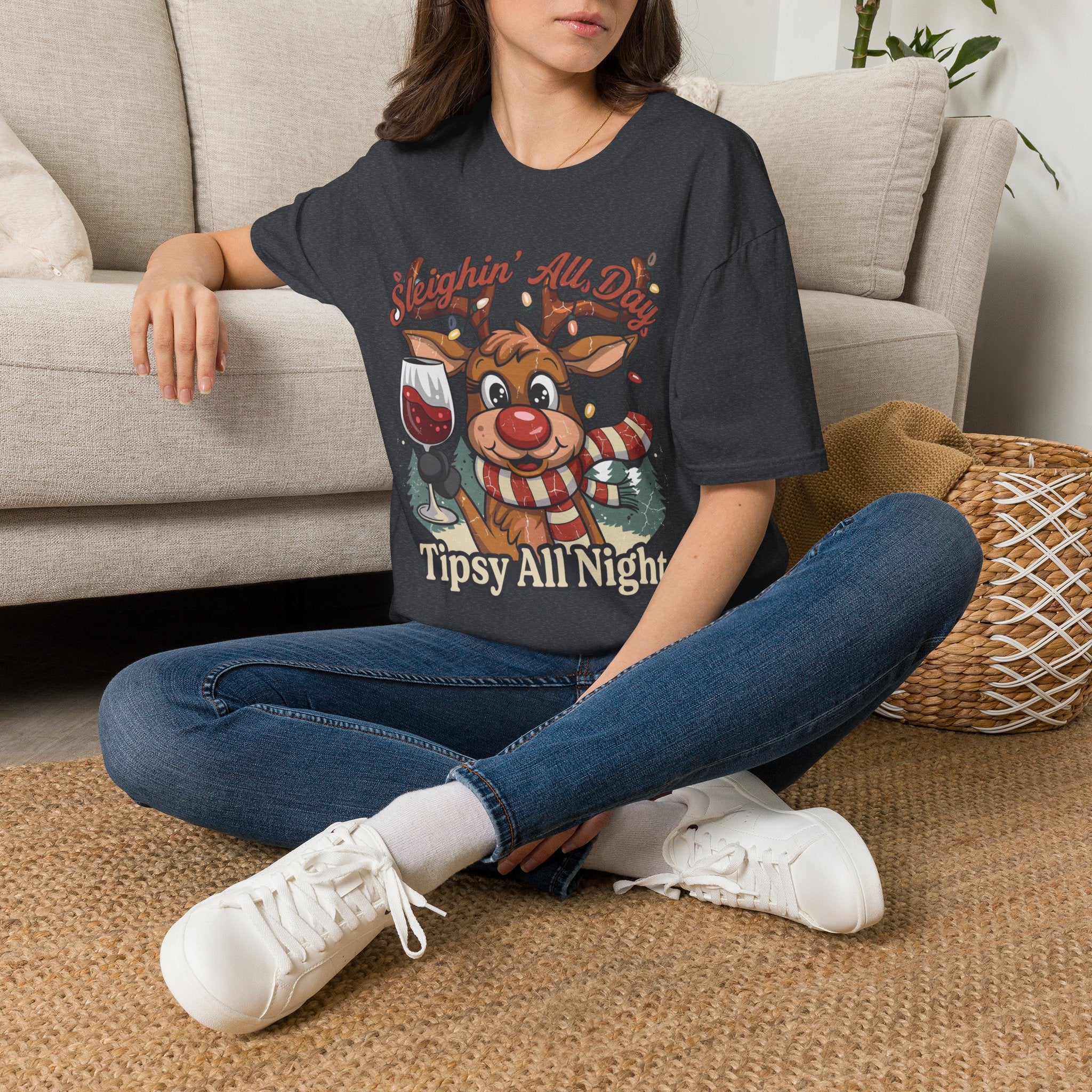 Reindeer Sleighin' All Day Tipsy All Night t-shirt in Dark Heather Grey, worn by a woman seated on a rug