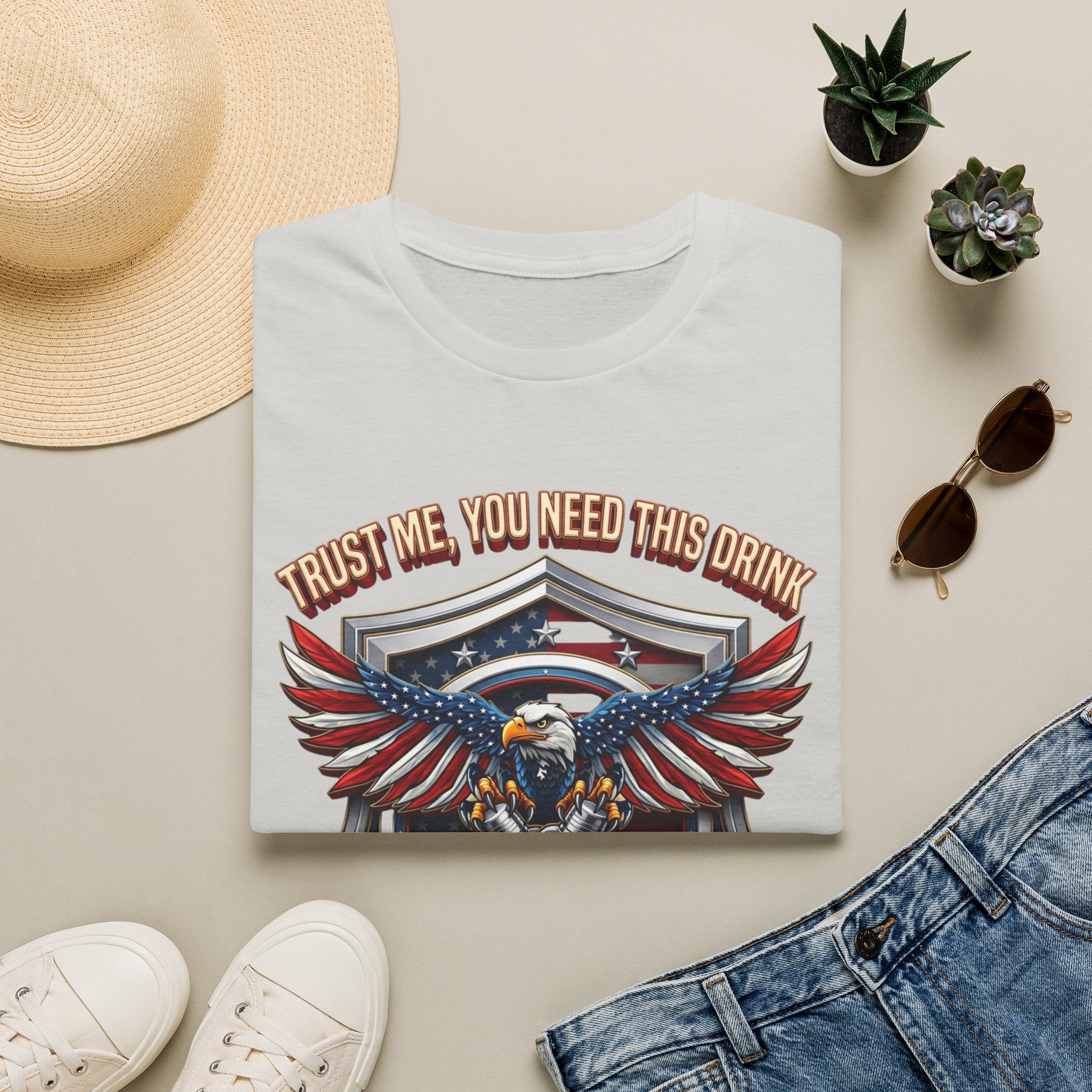 Bartender Eagle Trust Me You Need This Drink print on an Ice Grey t-shirt, folded beside a straw hat and jeans
