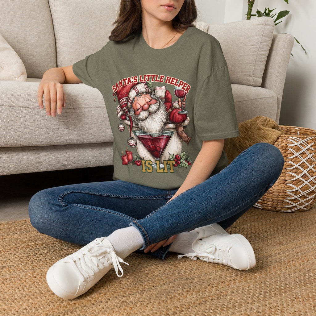 Santa's Little Helper Is Lit Christmas Wine t-shirt in Heather Military Green, worn by a woman seated on a rug