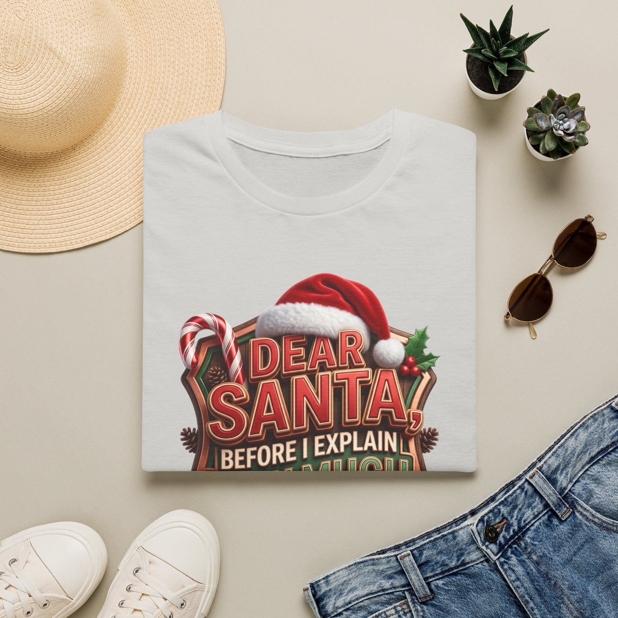 Dear Santa Before I Explain print on an Ice Grey t-shirt, folded beside a straw hat and jeans