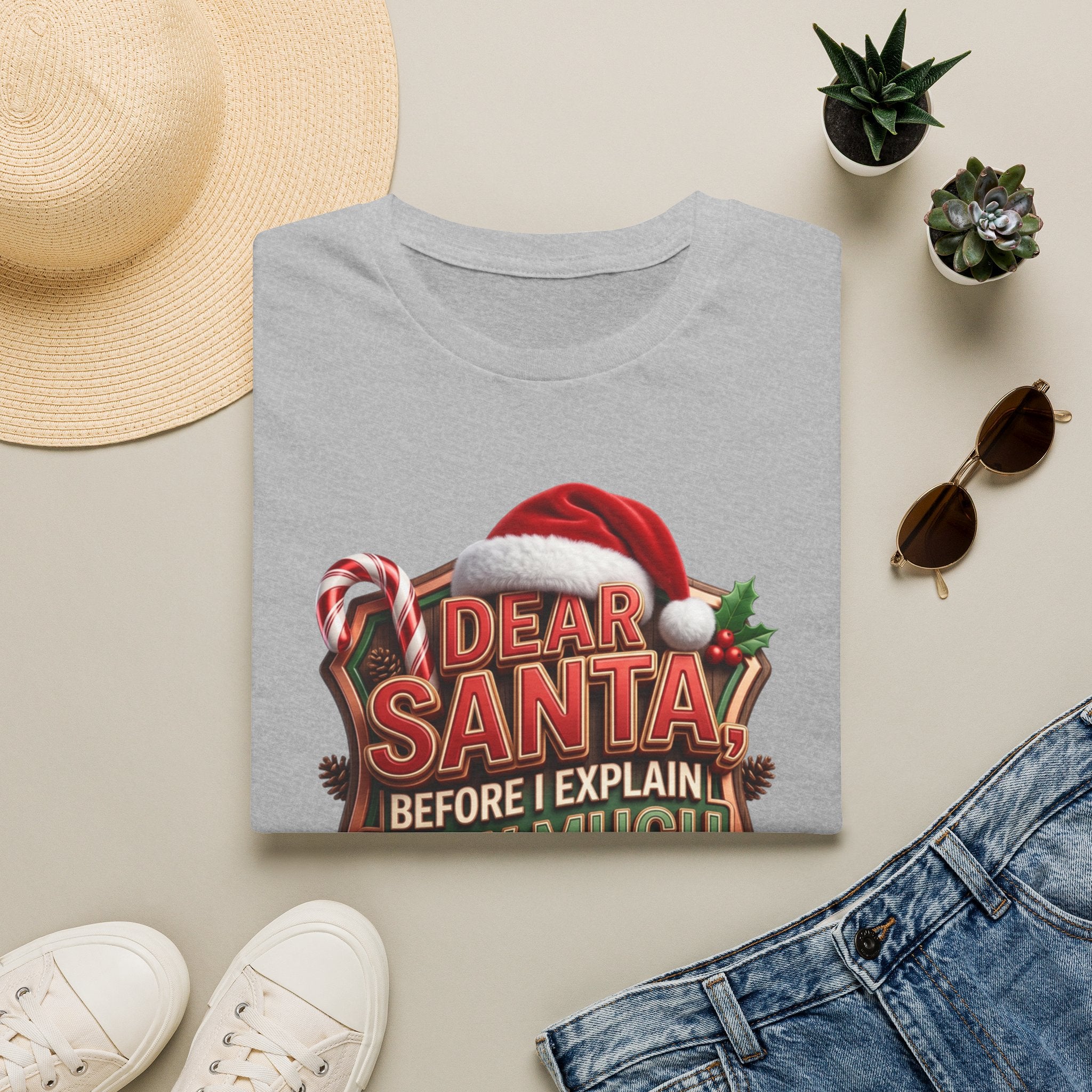 Dear Santa Before I Explain print on a Sport Grey t-shirt, folded beside a straw hat and jeans