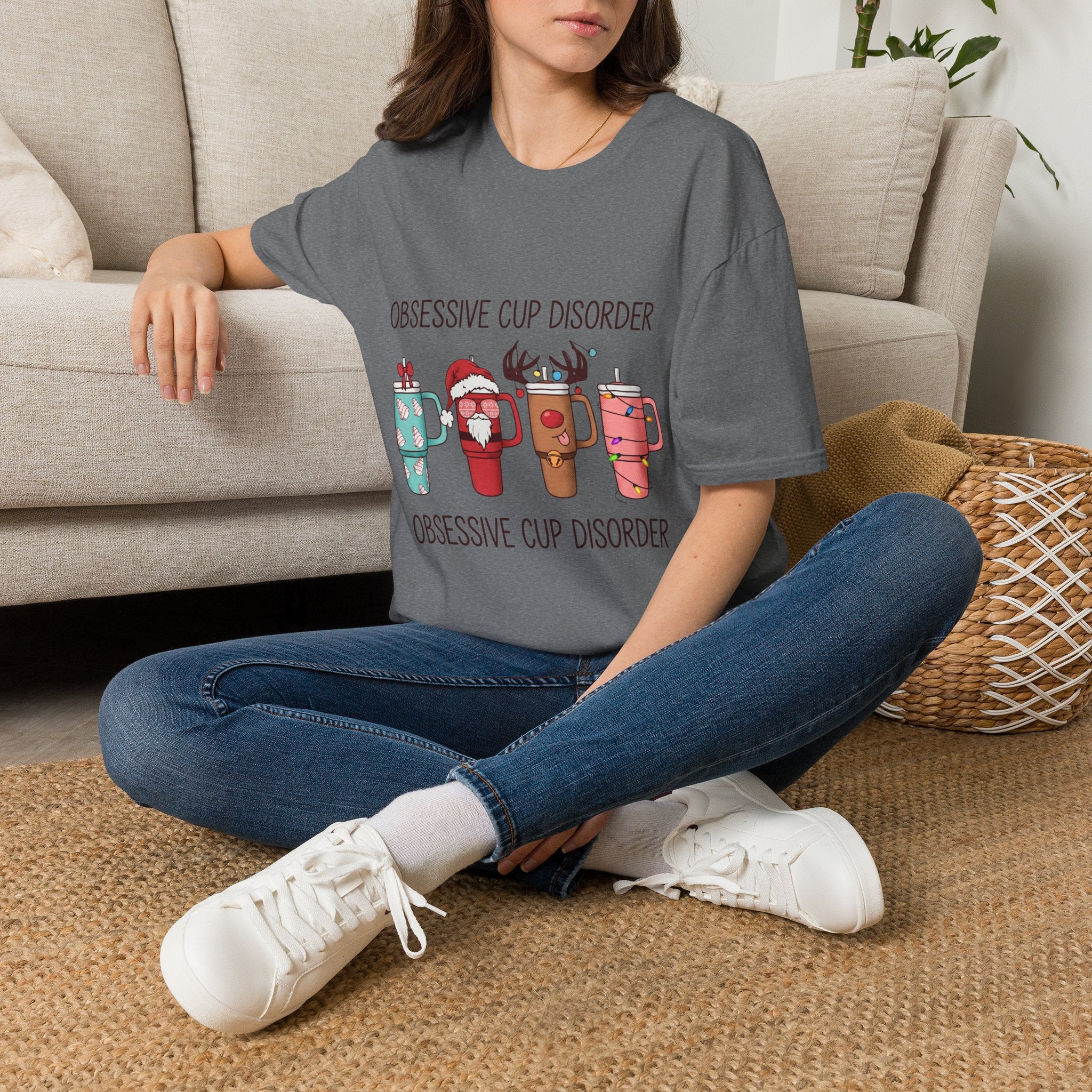 Obsessive Cup Disorder Funny Christmas Tumbler t-shirt in Graphite Heather, worn by a woman seated on a rug