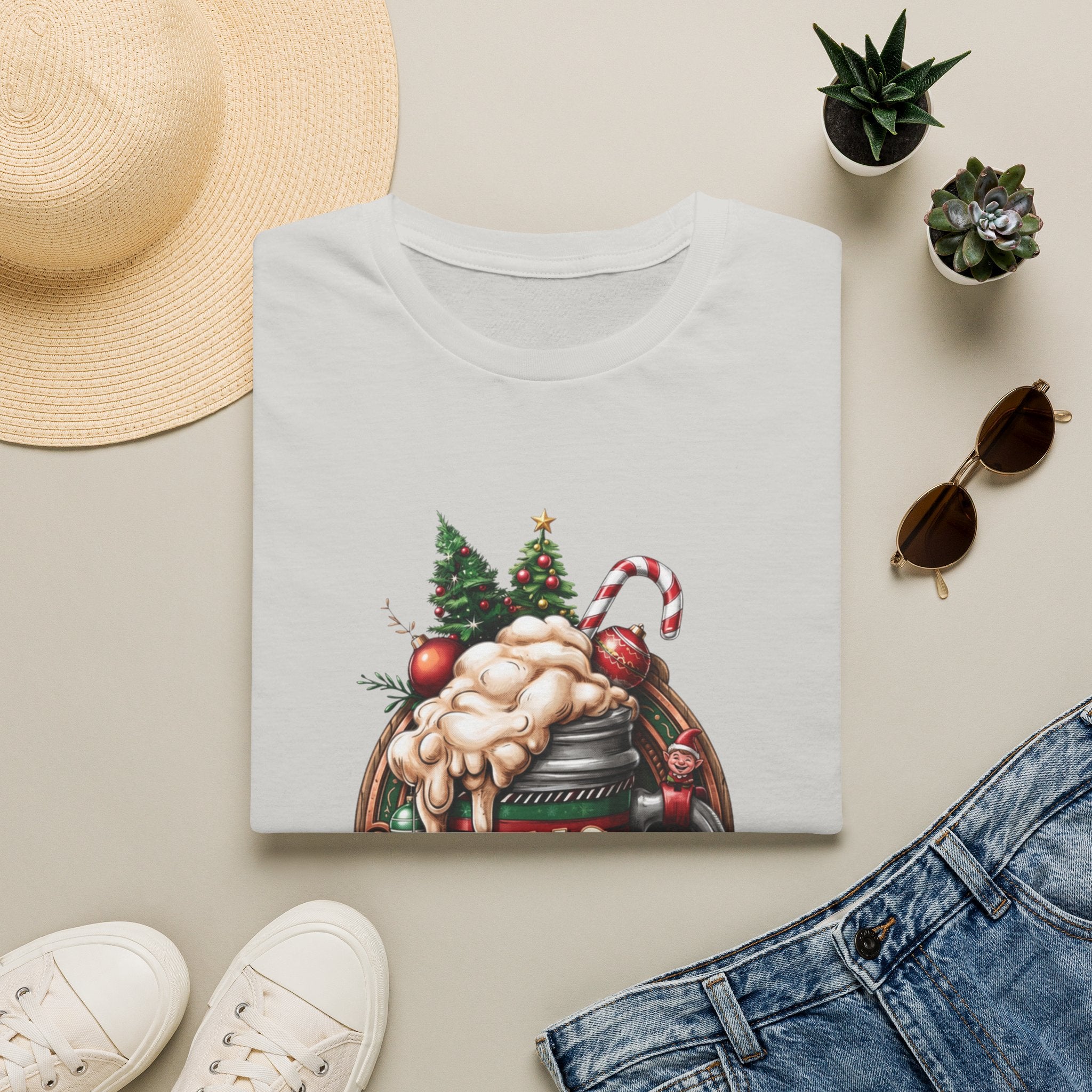 XMAS Beer Pour Me a Very Merry Christmas print on an Ice Grey t-shirt, folded beside a straw hat and jeans