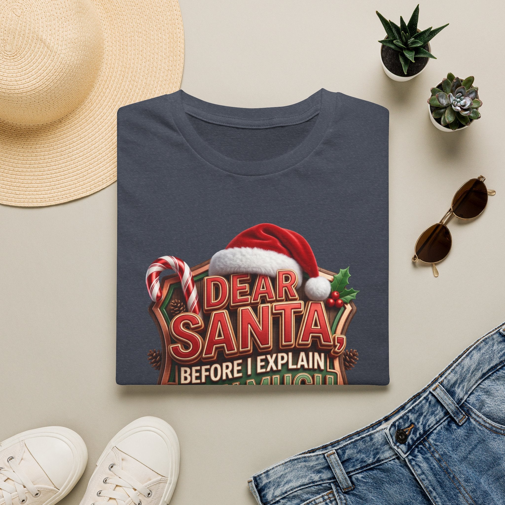 Dear Santa Before I Explain print on a Heather Navy t-shirt, folded beside a straw hat and jeans