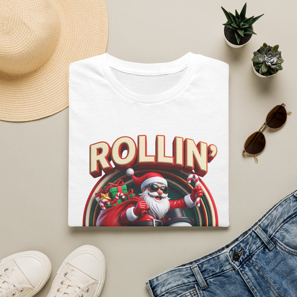 Rollin' with My Snowmies Santa & Snowman print on a White t-shirt, folded beside a straw hat and jeans