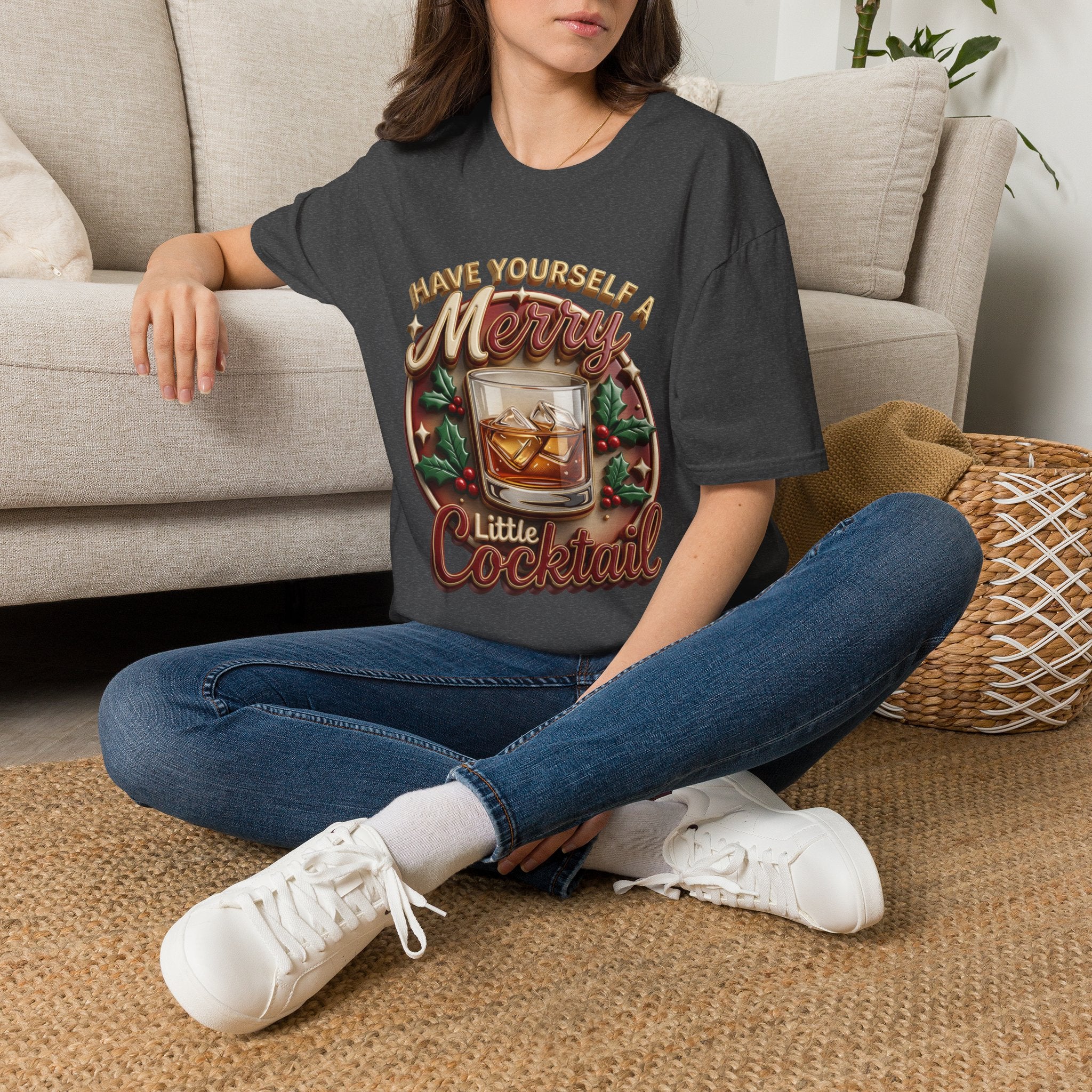 Have Yourself a Merry Little Cocktail t-shirt in Dark Heather, worn by a woman seated on a rug