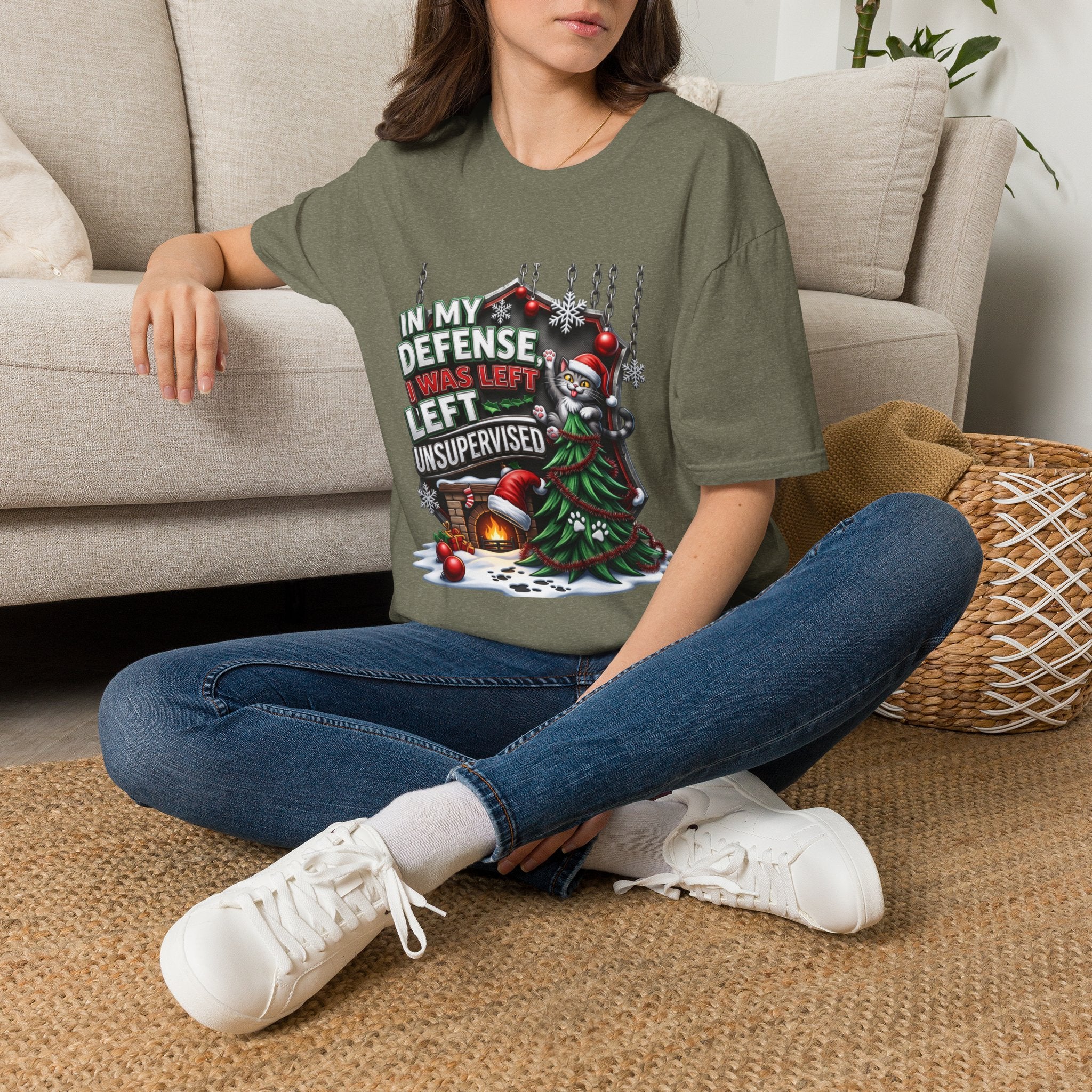 Cat In My Defense Left Unsupervised t-shirt in Heather Military Green, worn by a woman seated on a rug