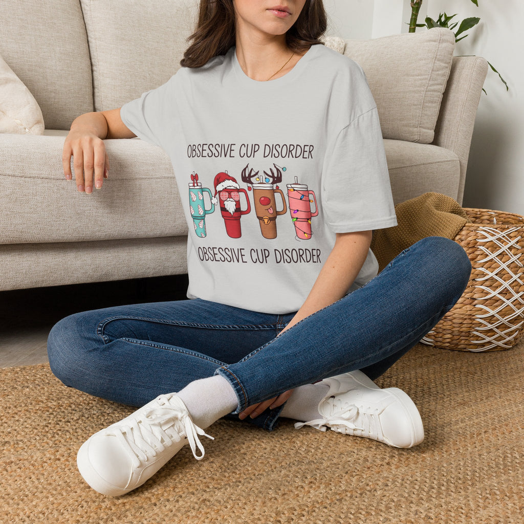 Obsessive Cup Disorder Funny Christmas Tumbler t-shirt in Ice Grey, worn by a woman seated on a rug