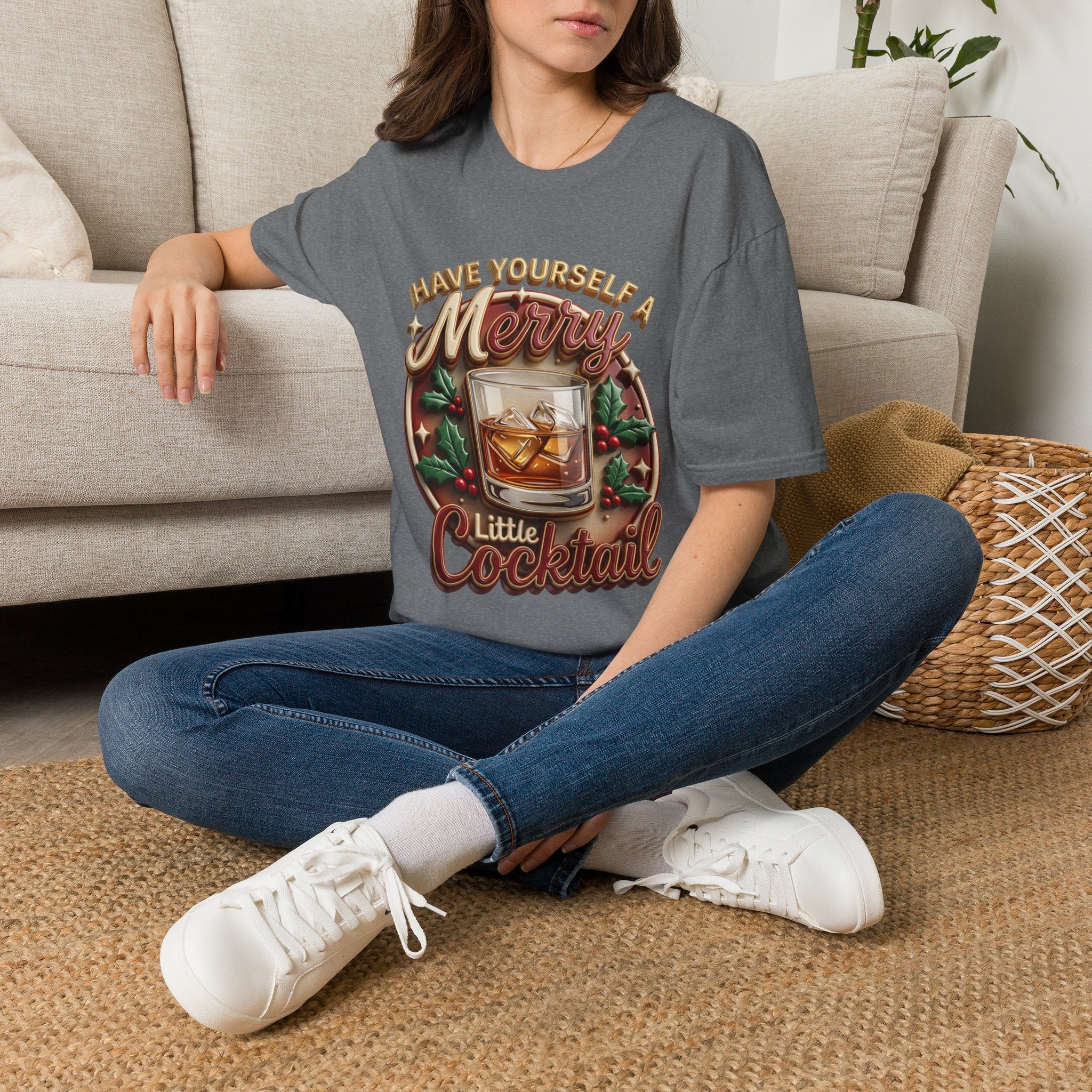 Have Yourself a Merry Little Cocktail t-shirt in Graphite Heather, worn by a woman seated on a rug