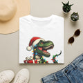 Happy Saurus T-Rex Santa Hat Christmas Lights print on a White t-shirt, folded beside a straw hat and jeans