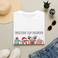 Obsessive Cup Disorder Funny Christmas Tumbler print on a White t-shirt, folded beside a straw hat and jeans