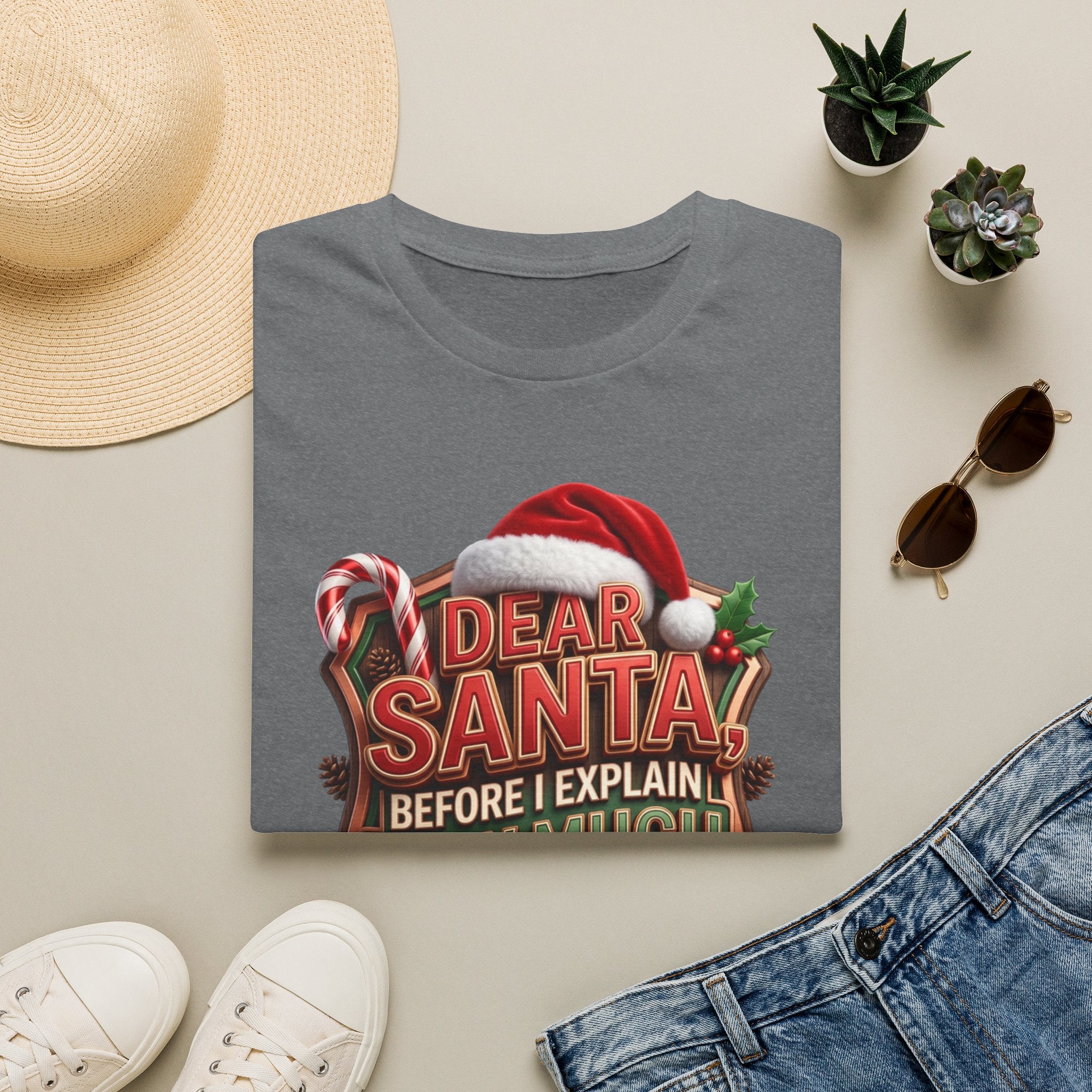 Dear Santa Before I Explain print on a Graphite Heather t-shirt, folded beside a straw hat and jeans