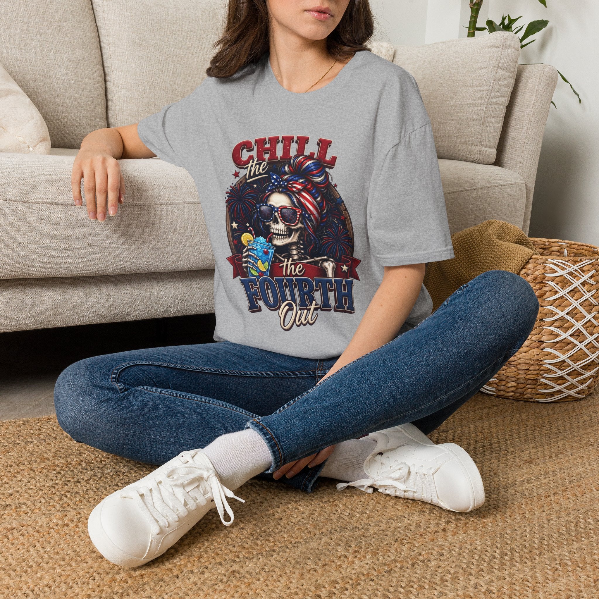 Chill the Fourth Out Patriotic Skeleton 4th of July t-shirt in Sport Grey, worn by a woman seated on a rug